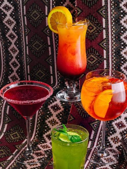 Vibrant array of mixed drinks on an intricate patterned background, suitable for a festive occasion